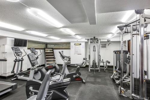 un gimnasio con varias cintas de correr y máquinas cardiovasculares en Hawaiian Monarch 2508 condo en Honolulu