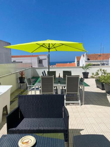 a patio with a table and a yellow umbrella at Sunset House / Casa Por do Sol in Nazaré