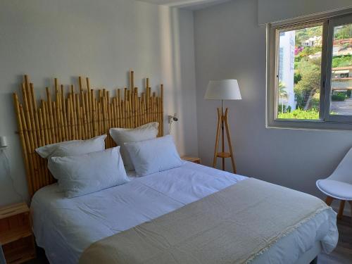 a bedroom with a bed with white sheets and a window at Vue mer exceptionnelle in Le Lavandou