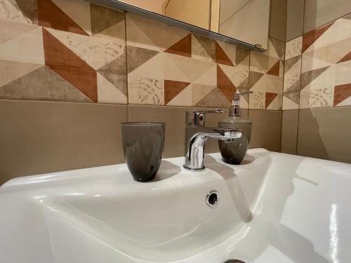 Un lavabo de baño con un grifo y dos tazas. en “I Niputeddi”, en Nicolosi