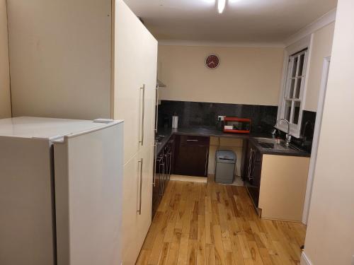 a kitchen with white cabinets and a wooden floor at Vetrelax Ipswich Woodbridge Apartment in Ipswich