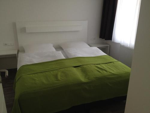 ein Schlafzimmer mit einem Bett mit einer grünen Decke darauf in der Unterkunft Aparthotel am Heidensee in Schwerin