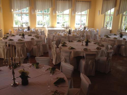 a room full of tables with white table settings at Aparthotel am Heidensee in Schwerin