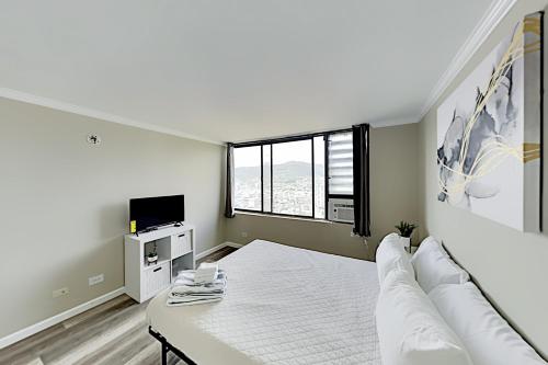 a white bedroom with a bed and a tv at Hawaiian Monarch 3707B condo in Honolulu