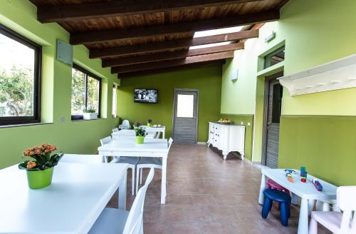 a dining room with white tables and green walls at Miss Sicily B&B in Terrasini