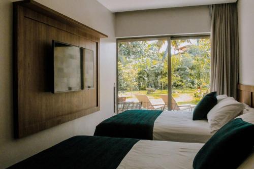 Habitación de hotel con 2 camas y ventana en Qavi - Flat completo com piscina privativa #ÎledePipa, en Pipa