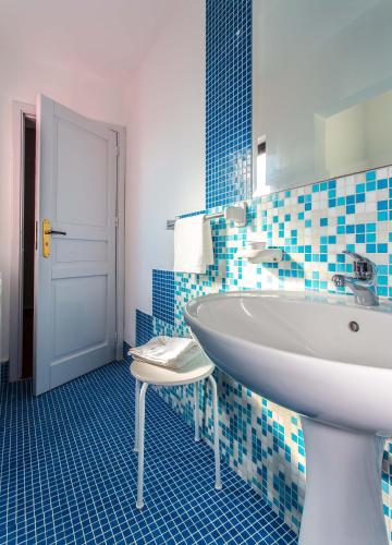 a bathroom with a white sink and blue tiles at Miss Sicily B&B in Terrasini