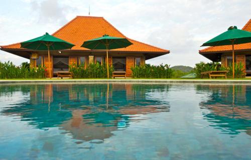 a resort with a swimming pool with green umbrellas at Three Monkeys Villas in Uluwatu