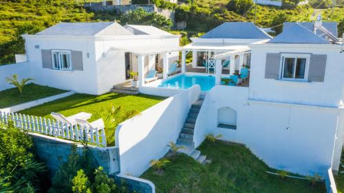 - une vue aérienne sur une maison blanche dotée d'une piscine dans l'établissement Au Temps D'antan- Ile Rodrigues, à Rodrigues Island