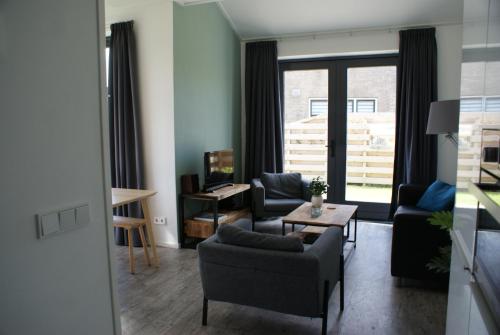 een woonkamer met een bank, stoelen en een tafel bij Antares-Ameland in Hollum