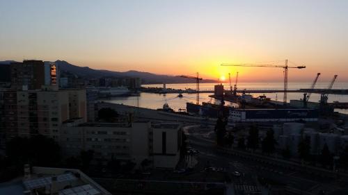 einen Sonnenuntergang über einer Stadt mit Kränen in der Unterkunft Mirador de Málaga in Málaga