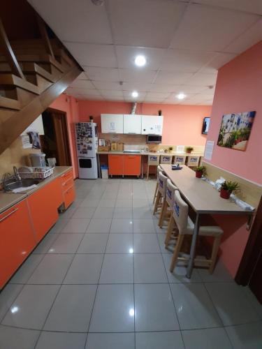 ノヴォシビルスクにあるХостел "Смородина-НСК"のキッチン(オレンジ色のキャビネット、テーブル、椅子付)