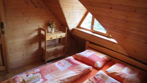 an attic bedroom with two beds and a table at Bungalov Tina in Žiar