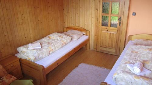 two beds in a room with wooden walls and wooden floors at Bungalov Tina in Žiar