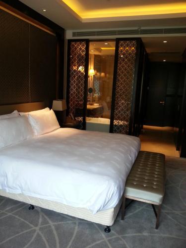 a bedroom with a large white bed and a bathroom at Primus Hotel Qipan Moutain Shenyang in Shenyang