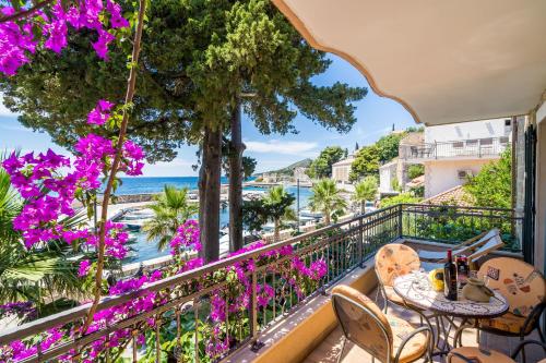 a balcony with a table and chairs and purple flowers at Apartments Villa Palma in Mlini