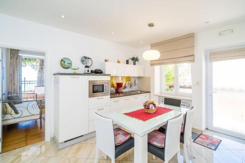 a white kitchen with a white table and chairs at Apartments Villa Palma in Mlini