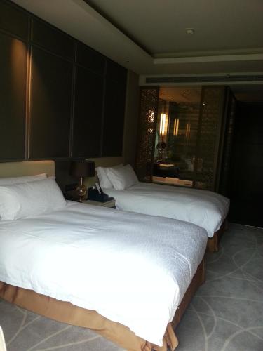 two beds in a hotel room with white sheets at Primus Hotel Qipan Moutain Shenyang in Shenyang