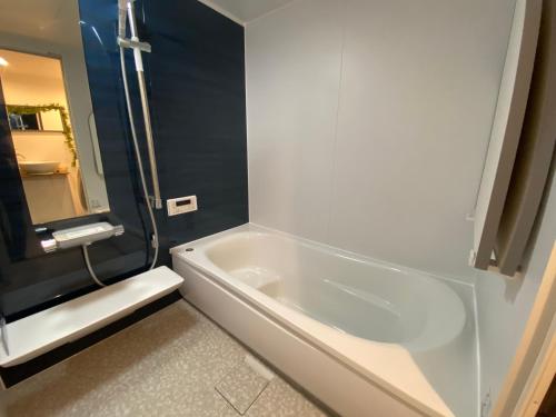 eine weiße Badewanne im Bad mit Spiegel in der Unterkunft Ray House in Yokohama