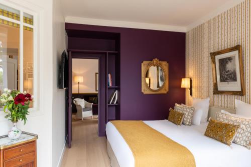 a bedroom with a king sized bed and purple walls at Hôtel Le Saint Christophe in La Baule