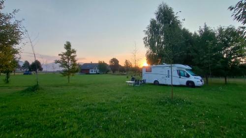 a white truck parked in a field with the sun setting at Bed & Breakfast Na Poljani in Kranj