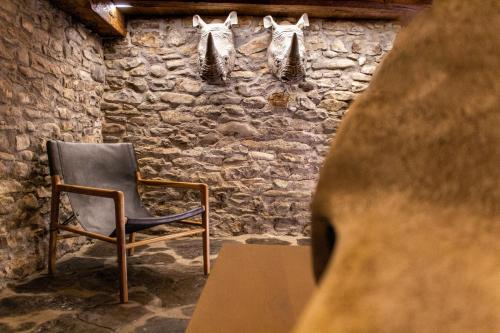 a chair sitting in a room with a stone wall at Casa Rural Aracanciás in Borrastre