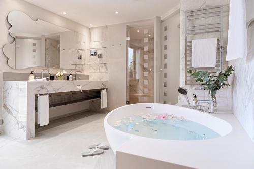 ein weißes Badezimmer mit einer Badewanne und einem Waschbecken in der Unterkunft Hotel Eden Roc - The Leading Hotels of the World in Ascona