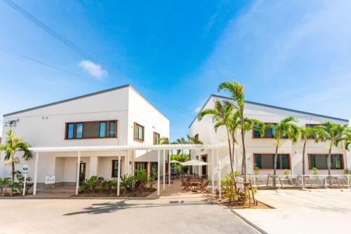 a white building with palm trees in front of it at Hotel California Miyakojima Resort in Miyako Island