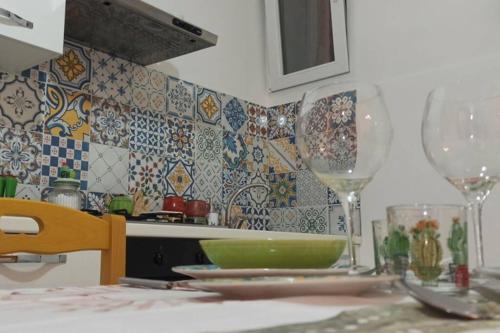 a kitchen with two wine glasses on a table at Casa Annita, casa vacanza in stile Sicilia, in pieno centro a Pachino in Pachino