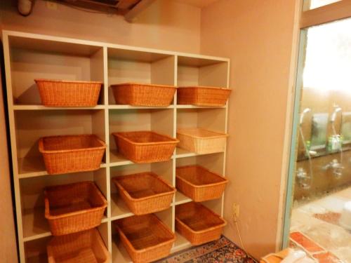 a book shelf with baskets on it in a room at Nakayasu Ryokan in Kanazawa