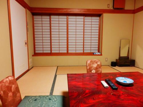 Habitación con mesa, sillas y ventana en Nakayasu Ryokan en Kanazawa