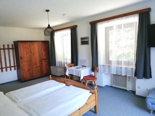 a bedroom with two beds and a table and two windows at Haus Oswald am See in Hermagor