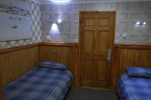 a room with two beds and a wooden door at The Steading Highland Glen Lodge in Drumnadrochit