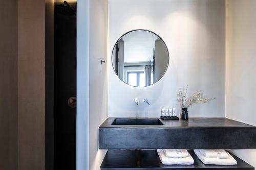 baño con lavabo negro y espejo en Nimbus Santorini, en Oia
