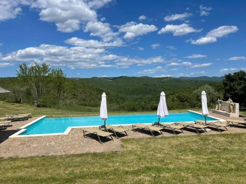 a swimming pool with chairs and umbrellas at L'Aiolina in Vagliagli