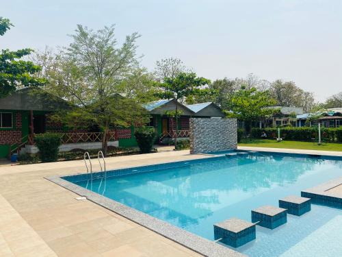 a swimming pool in a yard with a house at Lighthouse Waterpark and Resort in Mansar