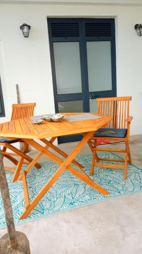 a wooden picnic table and two chairs on a rug at Lazy Lizard by the Ocean in Seixal
