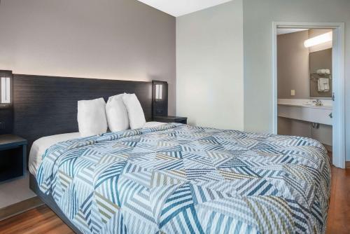 a bedroom with a bed with a blue and white comforter at Motel 6-Montgomery, AL - Airport in Hope Hull