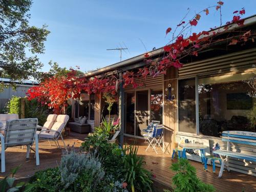 a patio with chairs and tables and red vines at Little Port Cottage in Portarlington