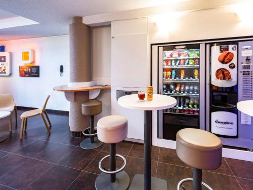 a fast food restaurant with tables and a refrigerator at ibis budget Orange Centre in Orange
