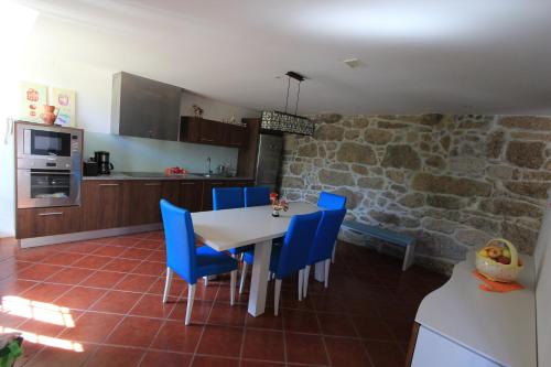 a kitchen and dining room with a table and blue chairs at Quinta Miranda in Geraz do Lima