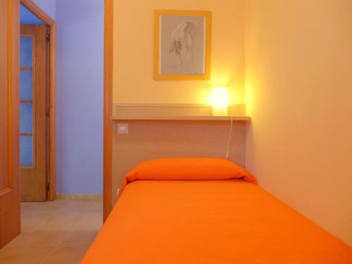 a small room with a bed with an orange blanket at Rentalmar Diplomatic Park in Salou