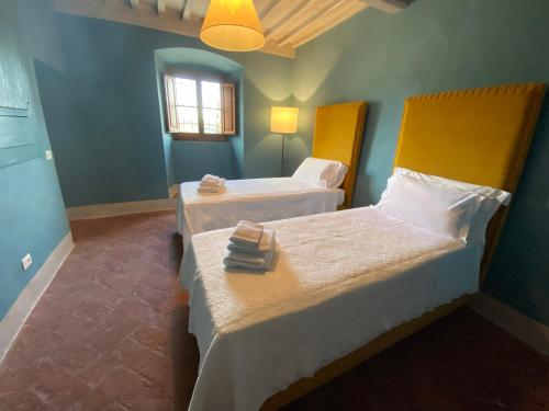 a room with two beds and a window at Castello Di Meleto in Gaiole in Chianti