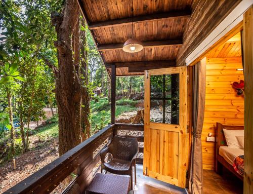 a cabin with a porch with a bed and a window at Nirvana Hill Resort in Curtorim