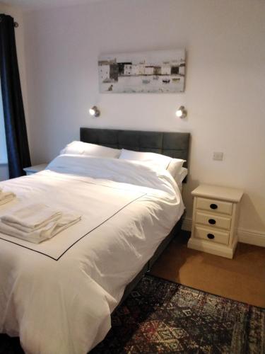 1 dormitorio con cama blanca y mesa auxiliar en The Ramblings, en Wexford