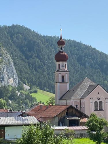 a church with a clock tower in front of a mountain at Apart Felsenheimerhof in Nassereith