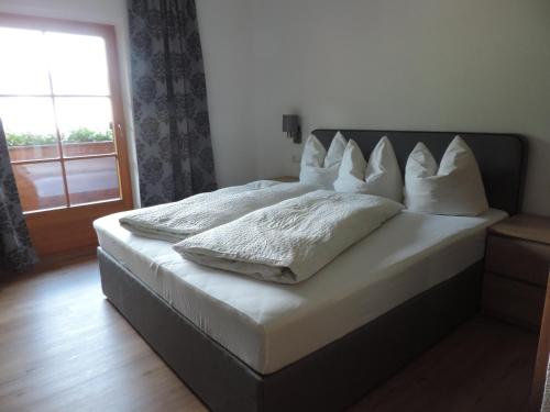 a bedroom with a bed with white pillows and a window at Pension Burgschroffen in Fendels