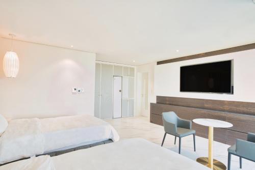 a bedroom with two beds and a tv on a wall at Villa de Aewol in Jeju