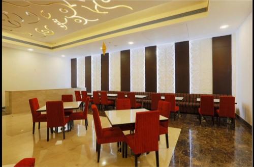 a dining room with red chairs and tables at Ramada Jamshedpur Bistupur in Jamshedpur