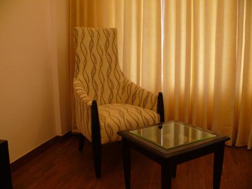 a room with a chair and a glass table at Ramada Jamshedpur Bistupur in Jamshedpur